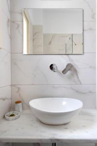 Baño blanco con lavabo y espejo en Villa Kalomira, en Spetses