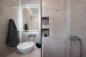 W łazience znajduje się umywalka oraz prysznic z lustrem. w obiekcie Sunwaves Beach studio II w mieście Jalisos