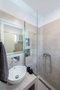 W łazience znajduje się biała umywalka i prysznic. w obiekcie Sunwaves Beach studio II w mieście Jalisos