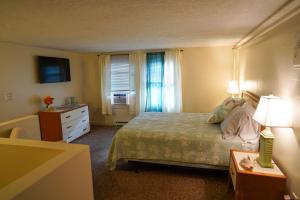 a bedroom with a bed and a dresser and a window at Portside Tavern in Hyannis