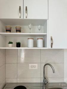 una cocina con estanterías blancas con vajilla y fregadero en Villa Senka, en Neum