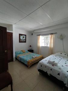 ein Schlafzimmer mit zwei Betten und einem Fenster in der Unterkunft Casa Bondigua in Santa Marta