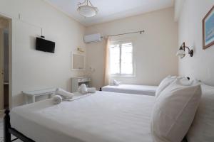 a white bedroom with two beds and a window at Villa Kalomira in Spetses