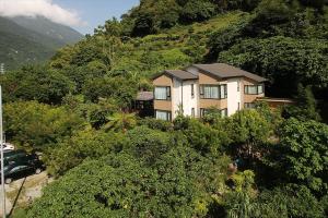 a house on the side of a hill with trees at Crossing The Rainbow Bridge B&B in Chongde