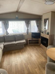 a living room with a couch and a television at The Oakley golden sands rhyl in Kinmel Bay