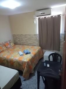 ein Schlafzimmer mit einem Bett, einem Tisch und einem Stuhl in der Unterkunft Pousada caminho das praias jp in João Pessoa