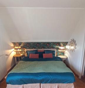 a bedroom with a blue bed with two tables at Gîte L'Escalier des Rêves - Rouen in Le Mesnil-Esnard