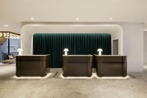 un vestíbulo con 2 escritorios y una pared verde en Le Méridien Melbourne en Melbourne