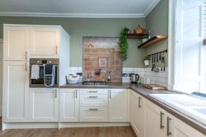 a kitchen with white cabinets and a brick wall at The Stirling Townhouse in Stirling