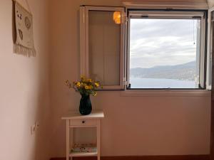 a vase of flowers sitting on a table next to a window at Perdika's Nest, family friendly house by the sea in Perdika