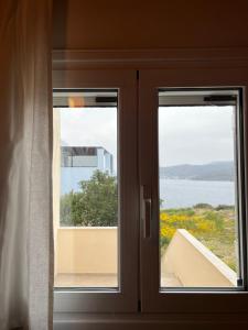 a door with two windows and a view of the water at Perdika's Nest, family friendly house by the sea in Perdika