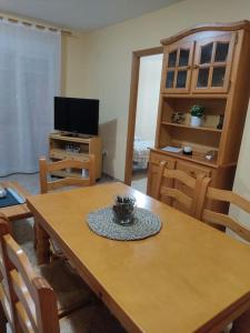 Habitación con mesa de madera con sillas y TV. en Precioso apartamento en Puerto de Sagunto Valencia, en Puerto Sagunto