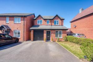 une maison en briques avec un garage en face de celle-ci dans l'établissement Skelhorn House, à Cosford