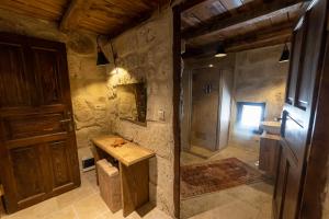 a stone bathroom with a sink and a wooden door at Feris Cave Hotel in Nevsehir