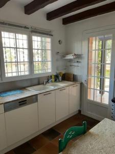 a kitchen with white cabinets and a sink and windows at Jolie Maison Piscine 8 mn à Pied du centre et Plage in Canet-en-Roussillon