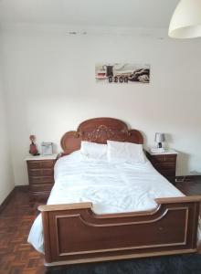- une chambre avec un grand lit et une tête de lit en bois dans l'établissement Quinta dos Linquetes, à Ourém
