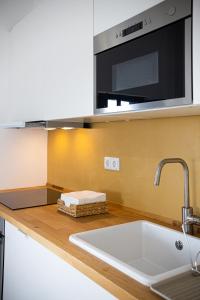 eine Küchentheke mit Spüle und Mikrowelle in der Unterkunft Aroucas Turismo e Natureza in Castro Marim