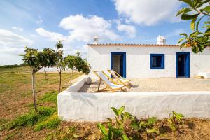 ein kleines weißes Haus mit zwei Stühlen davor in der Unterkunft Aroucas Turismo e Natureza in Castro Marim