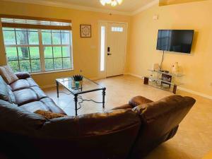 sala de estar con sofá de cuero y TV en Carlita's Home away from Home, en Lake Placid