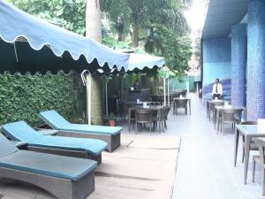 un restaurant avec des tables et des chaises bleues et une personne dans l'établissement Saj Luciya -A Classified 4 Star Hotel, à Trivandrum