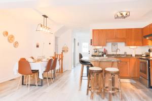 a kitchen with wooden cabinets and a table with bar stools at Stylish Boho Retreat- 5 Bed - 4 Bath - 15 min to Falls in Thorold
