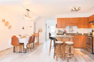 uma cozinha com armários de madeira e uma mesa com bancos de bar em Stylish Boho Retreat- 5 Bed - 4 Bath - 15 min to Falls em Thorold