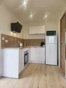 an empty kitchen with white appliances and wooden floors at bien situé entre mer et montage in Santa-Maria-di-Lota