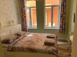 a bed in a bedroom with two windows at Студио Top City Center in Plovdiv
