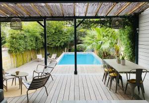 un patio con mesa, sillas y piscina en Family house Bordeaux centre, pool + garden, en Burdeos
