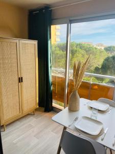 een kamer met een tafel met stoelen en een groot raam bij Studio Frejus plage in Fréjus