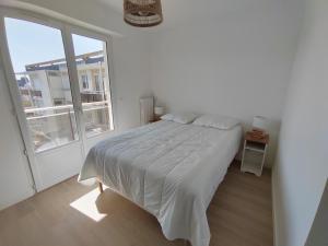 a white bedroom with a bed and a large window at Ker Romain - Sea View - 3 bedrooms Appt in Saint Malo
