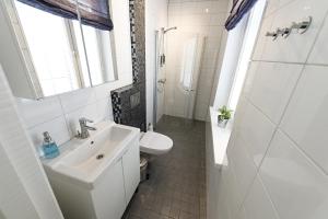 a white bathroom with a sink and a toilet at Townhouse Apartments in Mariehamn
