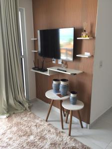 uma sala de estar com duas mesas e uma televisão em Lindo apartamento de férias à 100m do mar! em Cabedelo