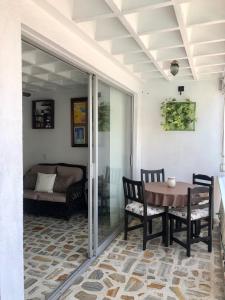 a patio with a table and chairs and a couch at Sobre Costera, 1min La Quebrada, 3m playas/yates in Acapulco