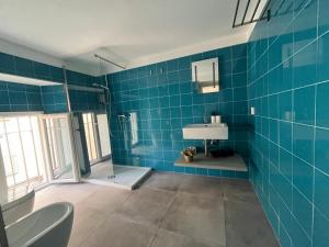 a blue tiled bathroom with a shower and a sink at Lucullo's Rooftop in Naples