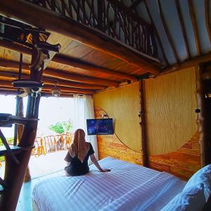 a woman sitting on a bed in a bedroom at Ama Awa Resort in Kemadang