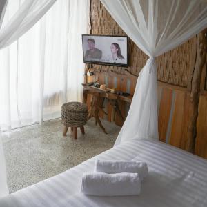Ama Awa Resort في Kemadang: غرفة نوم مع سرير وتلفزيون على الحائط