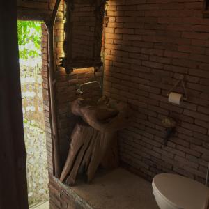 Ama Awa Resort في Kemadang: حمام مع حوض خشبي في جدار من الطوب