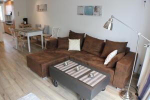 a living room with a brown couch and a table at Apartment "MS Nautic" hundefreundlich mit Südbalkon Sauna und Parkplatz - 200m zum Deich in Dorum-Neufeld