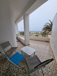 a balcony with a table and chairs and the ocean at Appartement vue mer in Mahdia