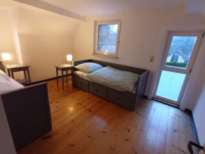 a bedroom with a bed and two windows and a wooden floor at Ferienhaus Naturparadies Rhön in Willmars