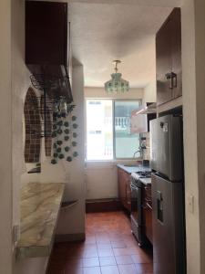 a kitchen with a stainless steel refrigerator and a window at Sobre Costera, 1min La Quebrada, 3m playas/yates in Acapulco