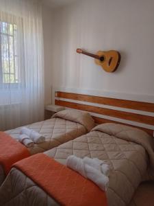 two beds in a room with a guitar on the wall at Villa Gemma in San Vito dei Normanni