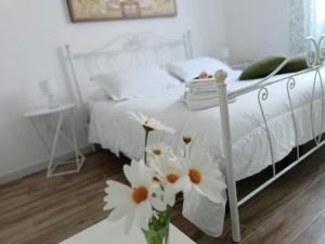 a white bed with flowers in a vase on a table at B&B Casa Alinella, Happy and Sustainable Hospitality in Taranto +38 photos