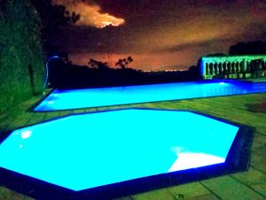 dwa baseny są oświetlone niebiesko w nocy w obiekcie POUSADA NOSSA SENHORA w mieście Penedo