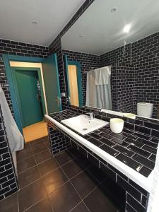 a bathroom with a white sink and black tiles at El encanto de un pueblo 