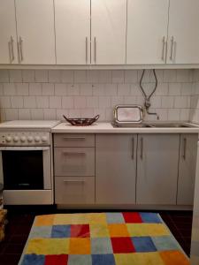 una cocina con armarios blancos y una alfombra colorida en el suelo en Villa Tajra Stolac, en Stolac