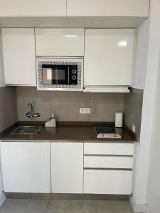 a kitchen with white cabinets and a microwave at 180 Home. Rincón de Triana in Seville
