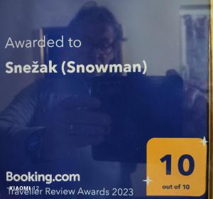 a person taking a picture of a sign in a window at Snežak (Snowman) in Bohinj