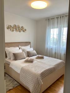 Portview apartment في رييكا: غرفة نوم بسرير وملاءات بيضاء ونافذة